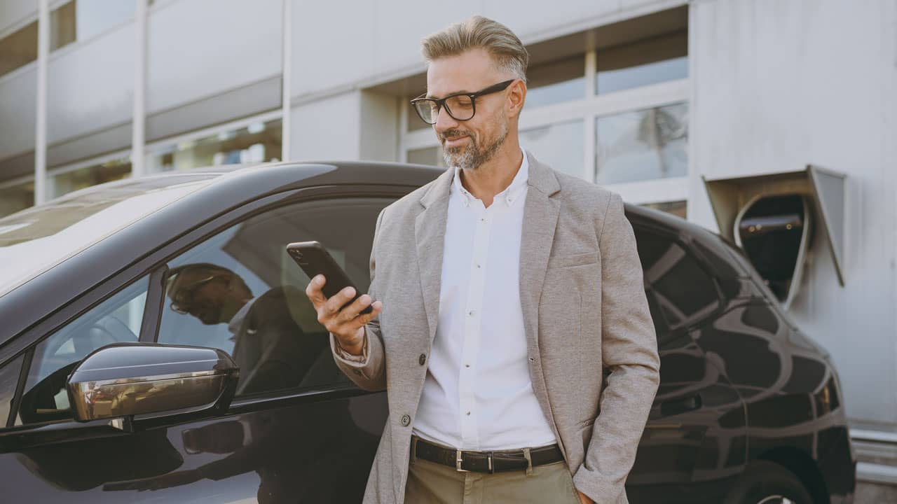 Autoabo Mann vor Auto mit Handy