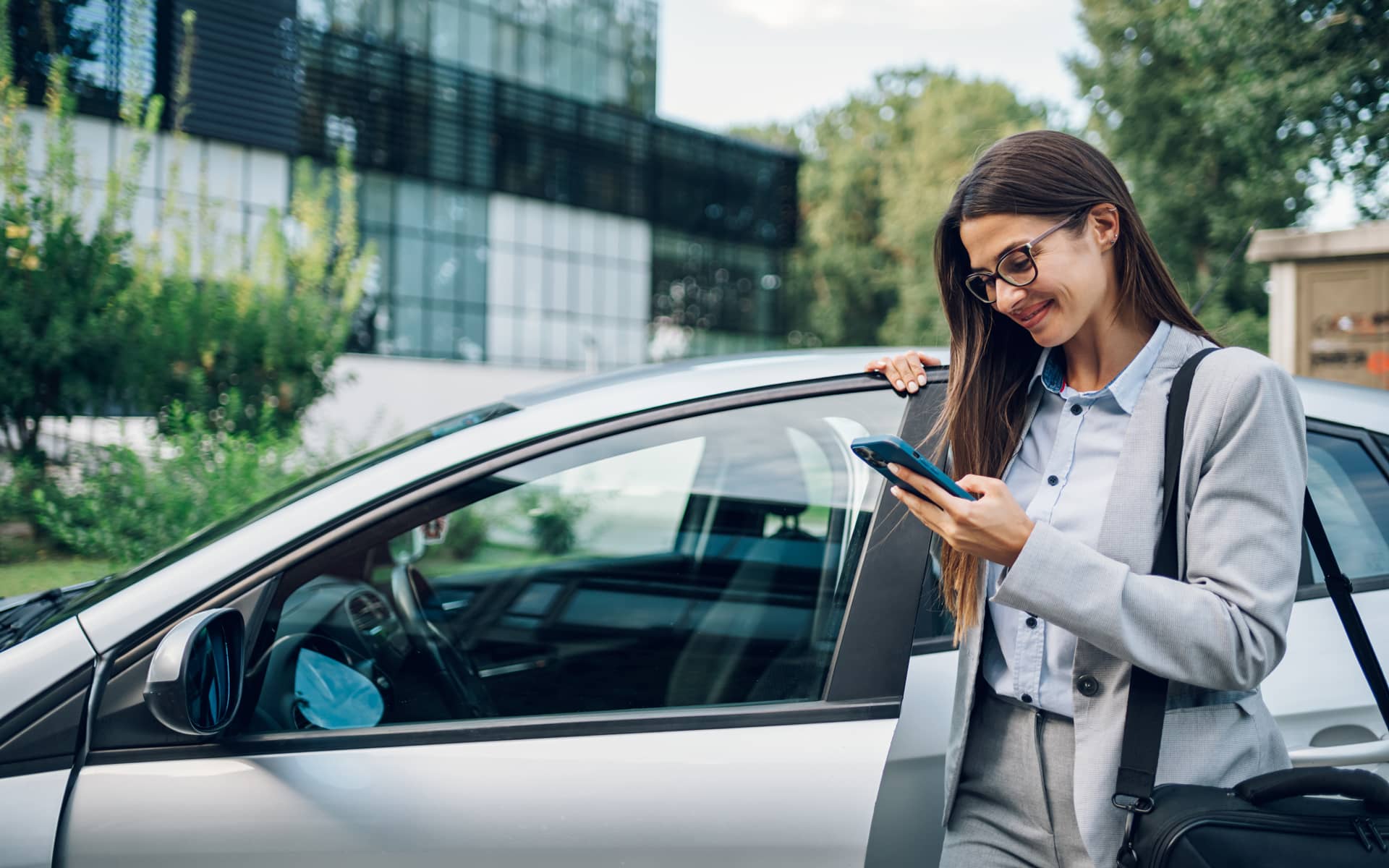 Frau an einer Autotür mit einem Smartphone